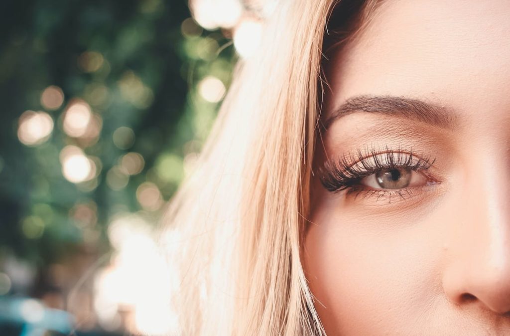 A close-up shot of a woman’s right eye that shows long, curled-up eyelashes during the daylight