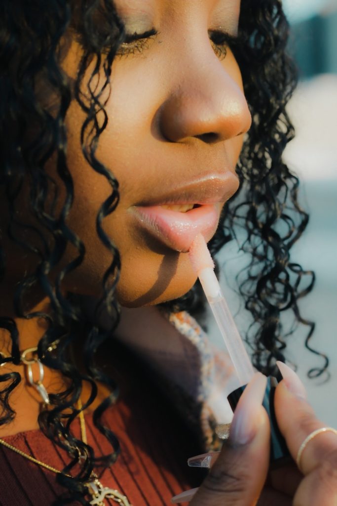 a woman applying lip gloss.